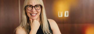 Portrait of Jane Doe who has long straight blond hair and black glasses